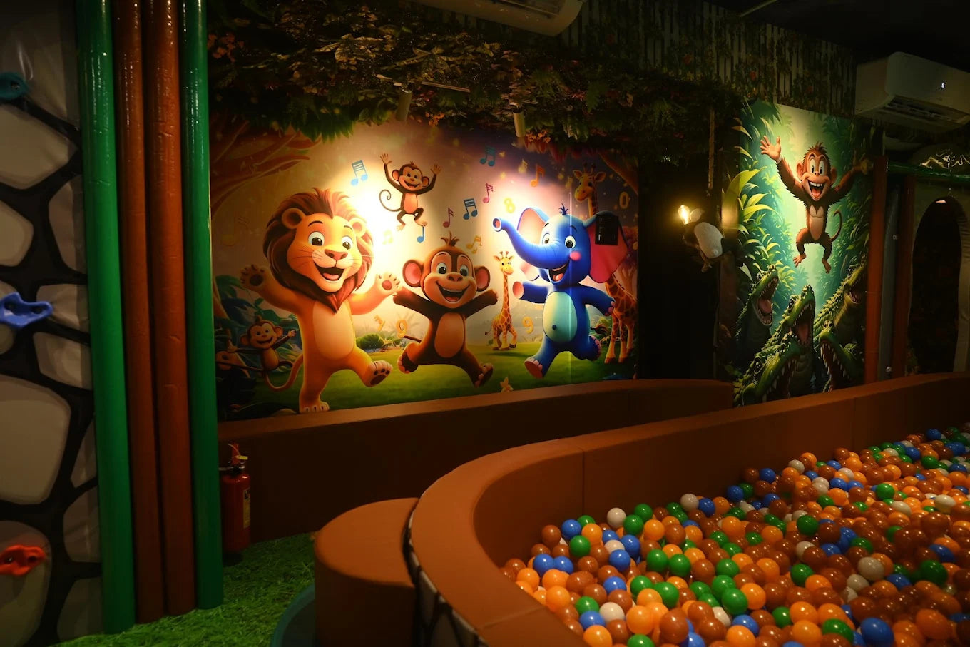 A colorful ball pit in a jungle-themed play area with cartoon animals on the wall.