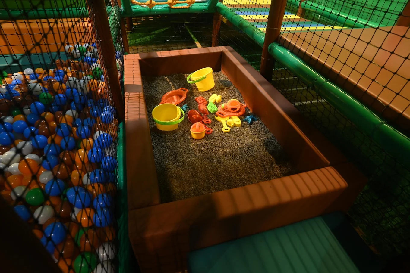 Children's play area with a ball pit and a sandbox filled with toys.