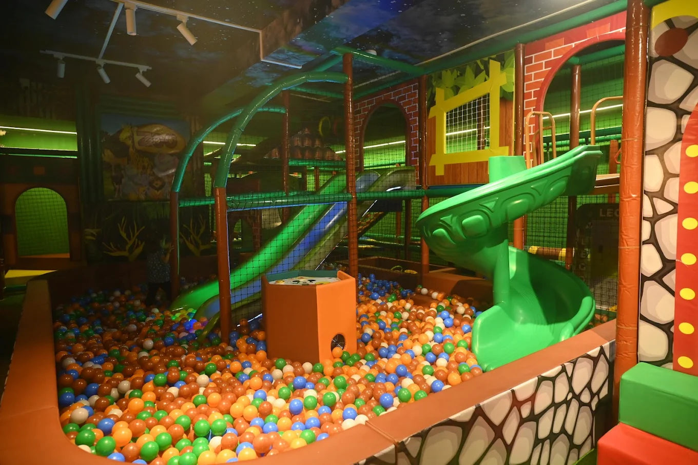 A colorful indoor playground with a ball pit and slides, where a child plays.
