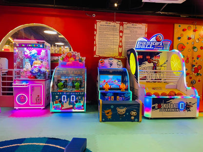 An arcade with colorful games for children, including a claw machine and basketball game.