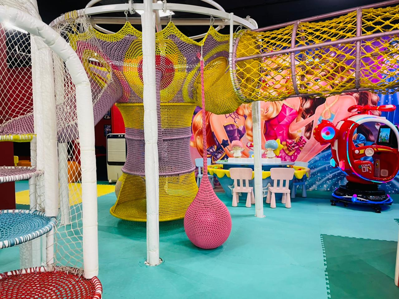 A colorful indoor playground with nets, slides, and a toy helicopter, designed for young children.