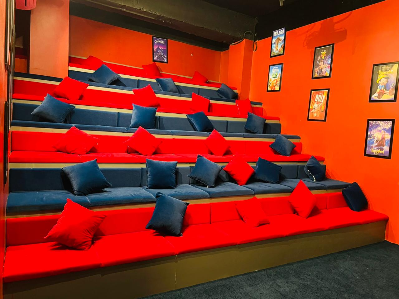 A tiered seating area with red and blue cushions, decorated with movie posters.