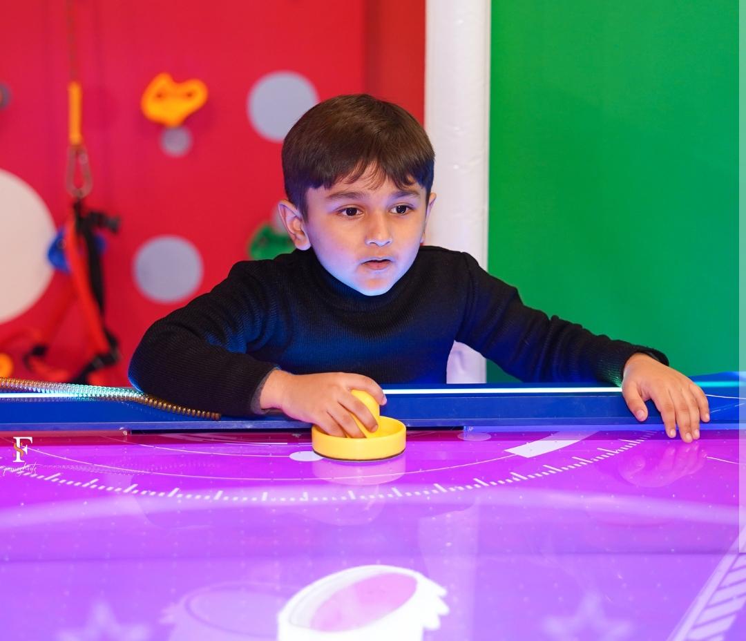 A young boy plays air hockey in an arcade.