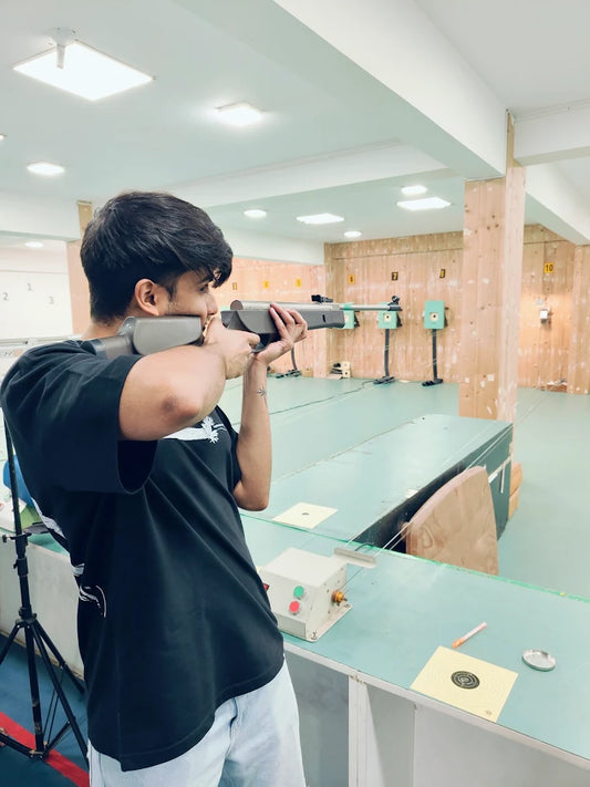 A young person aims a rifle at a shooting range.