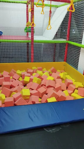 A ball pit filled with pink and yellow foam cubes in a children's indoor play area.
