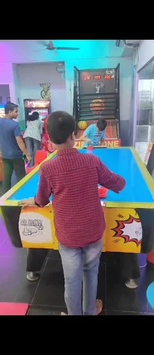 Children play air hockey in an arcade.