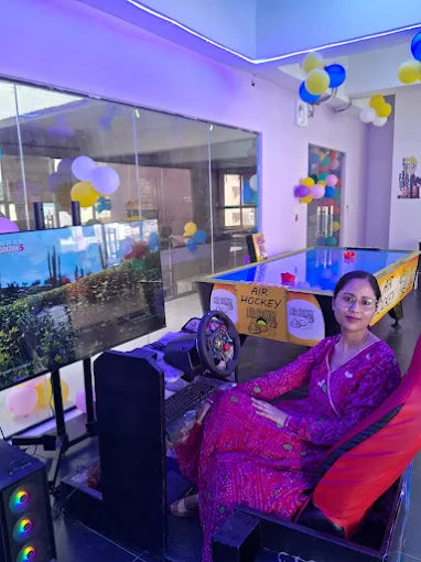 A woman plays a racing arcade game in a brightly lit entertainment center.