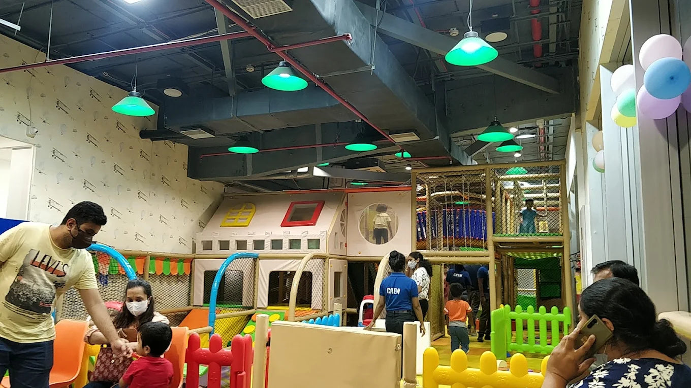 A family enjoys a colorful indoor playground with climbing structures and ball pits.