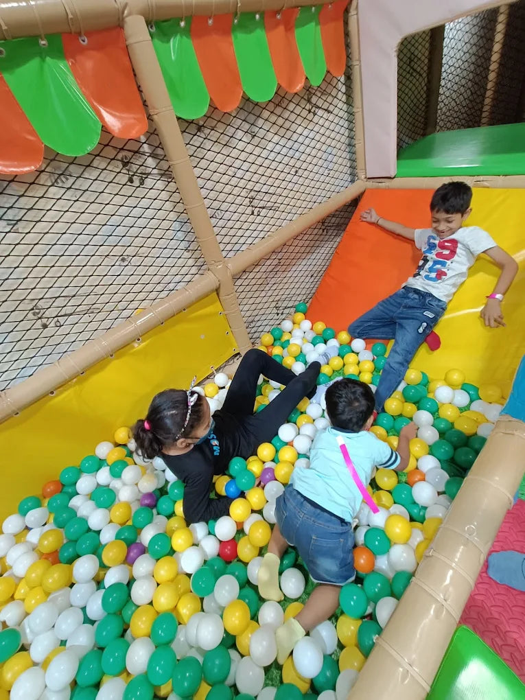 Children play in a ball pit at an indoor playground.