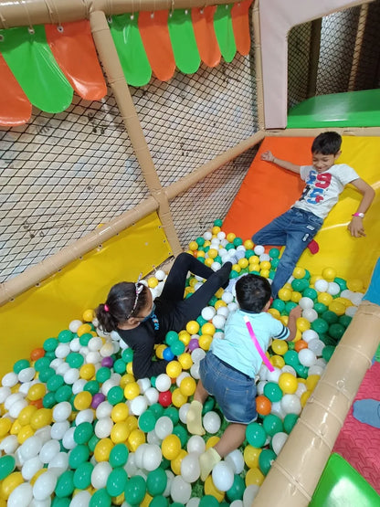 Children play in a ball pit at an indoor playground.