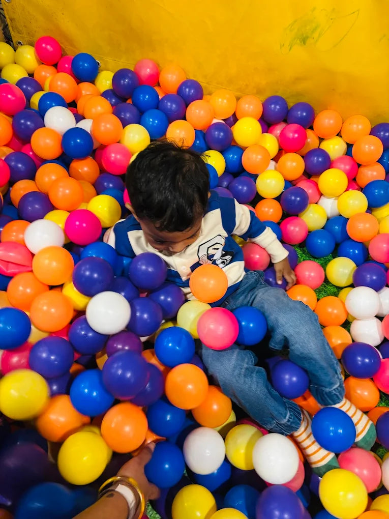 A young child plays in a ball pit filled with colorful balls.