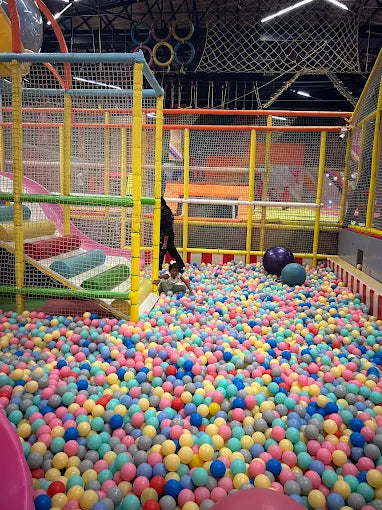Colorful ball pit with a child playing inside a play area.