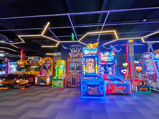 An arcade with various colorful games, including racing simulators and skill-based machines, illuminated by neon lights.