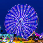 Amusement park at night with a large Ferris wheel and colorful lights.