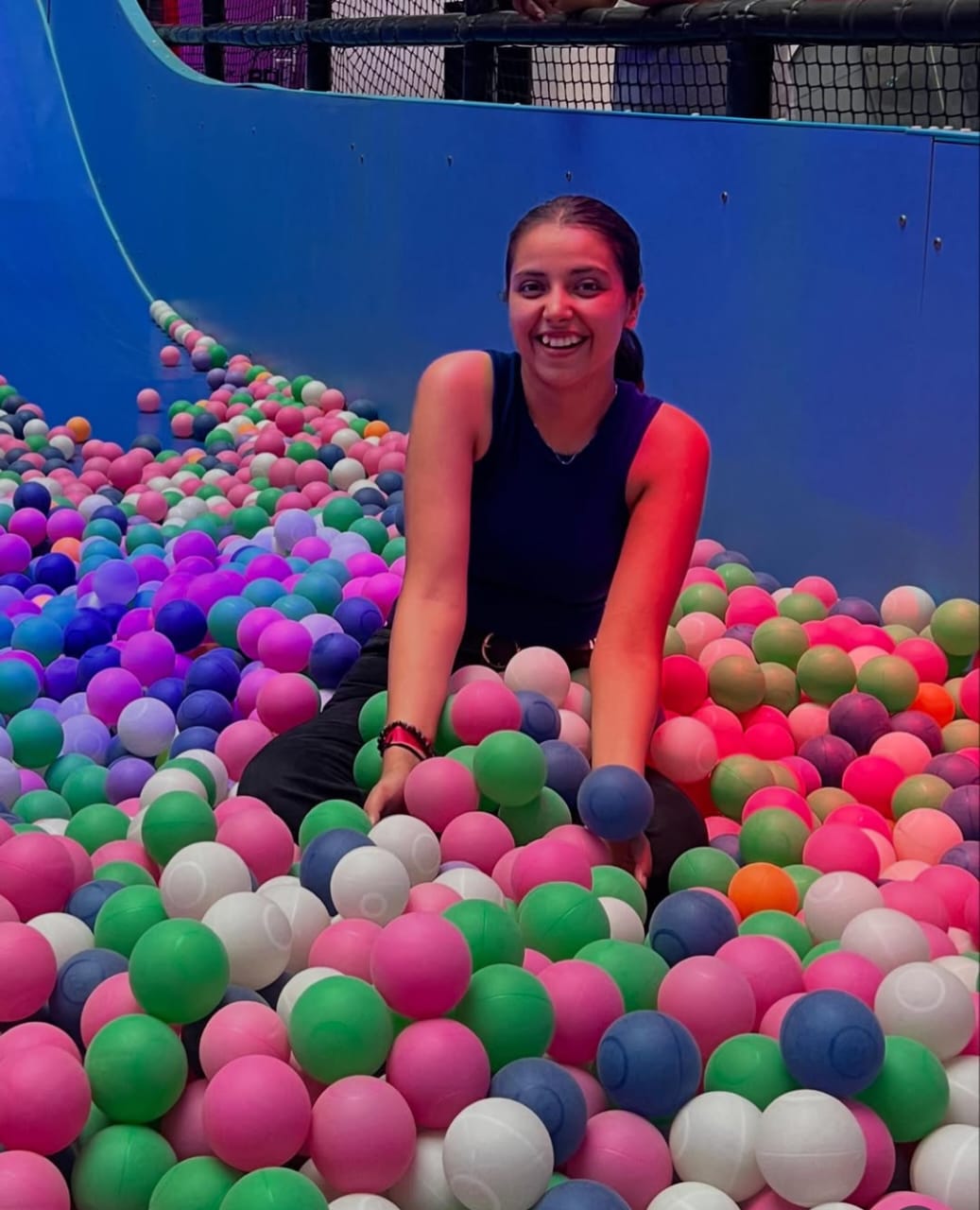 Person sitting in a ball pit filled with colorful balls