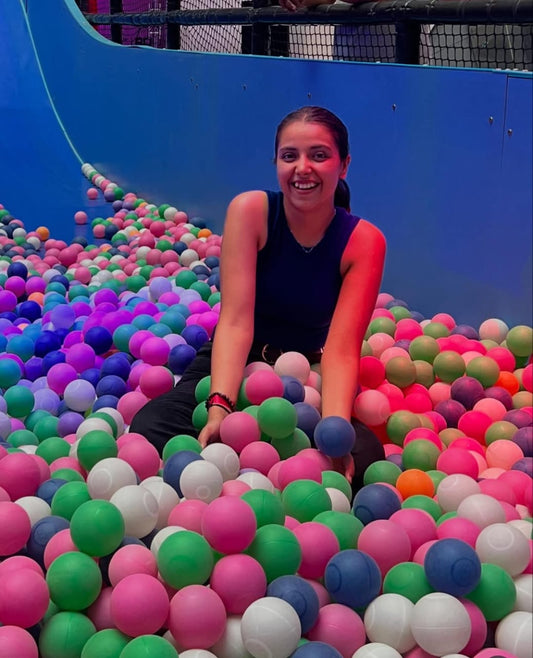 Person sitting in a ball pit filled with colorful balls