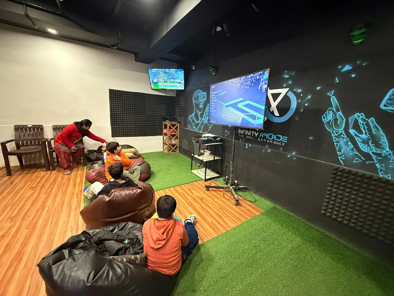 Children play video games in a VR arcade while a woman watches.
