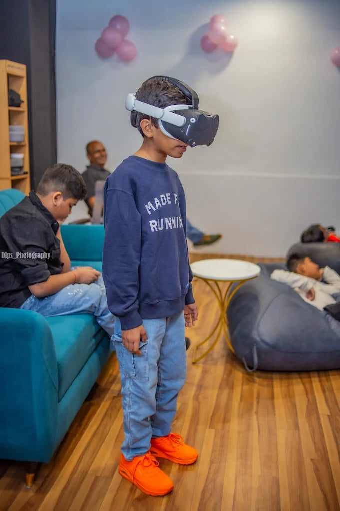 A young boy wearing a VR headset stands in a room with others, looking engaged.