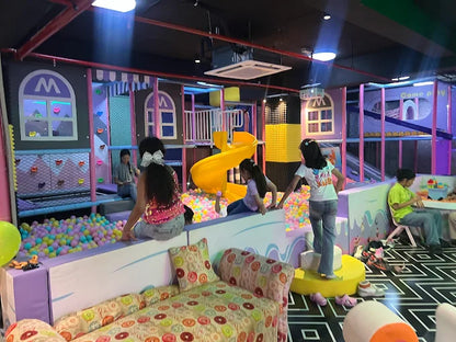 Children playing in a colorful indoor playground with slides and soft play areas.