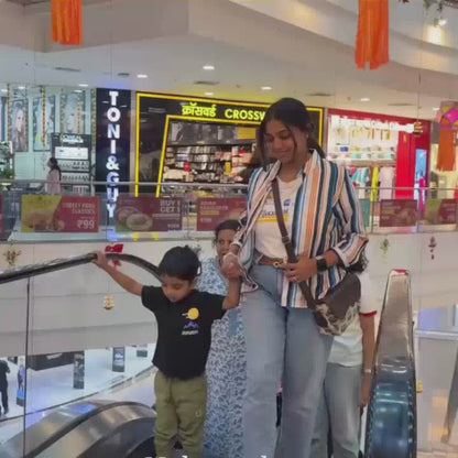A group of children and adults enjoy a vibrant indoor play area filled with colorful ball pits, slides, and trampolines. The atmosphere is lively and fun, with kids of various ages actively engaged in play. Notable attractions include a mirror maze, a basketball-themed trampoline area, and a kinetic sand play station.