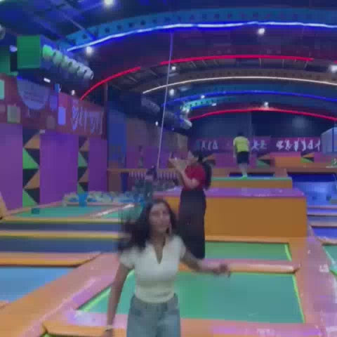A group of young people enjoys a vibrant indoor trampoline park filled with colorful foam cubes and bouncy surfaces. They are seen jumping, swinging, and playing in the foam pit, creating a lively and energetic atmosphere. The park features bright lights, padded obstacles, and various attractions designed for active fun.