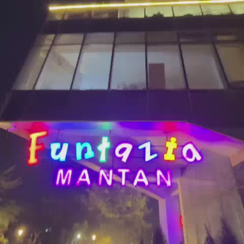 A vibrant indoor entertainment center offers a variety of activities for children and families. The space features a colorful ball pit with slides, a bowling alley with animated graphics, trampolines, and arcade games. The atmosphere is lively and fun, with bright lights and engaging attractions for all ages.