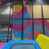 A vibrant indoor trampoline park buzzes with energy as people of all ages leap, climb, and swing. Colorful walls and trampolines create a playful atmosphere, while attractions like climbing walls and zip lines offer exciting challenges. The scene captures the joy and exhilaration of active fun.
