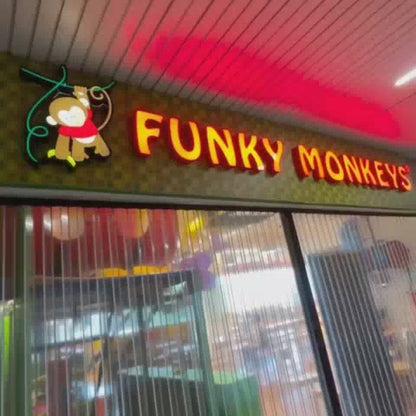 A young boy joyfully explores a vibrant indoor playground called "Funky Monkeys." He slides down colorful tubes, rides a bouncy zebra, and plays in a ball pit. The atmosphere is lively and fun, perfect for children's entertainment.
