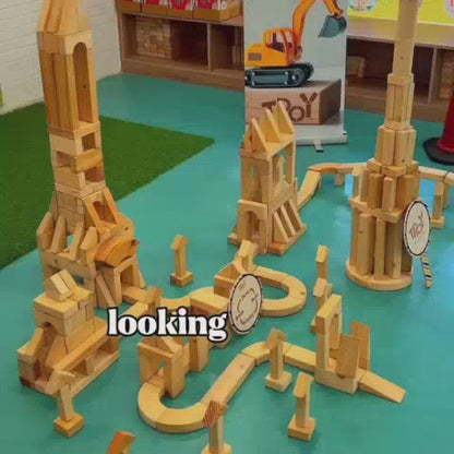Children engage in imaginative play with wooden blocks, building towers and structures in a vibrant, construction-themed fun center. The atmosphere is one of focused creativity and exploration, with colorful decorations and interactive elements designed for young minds.