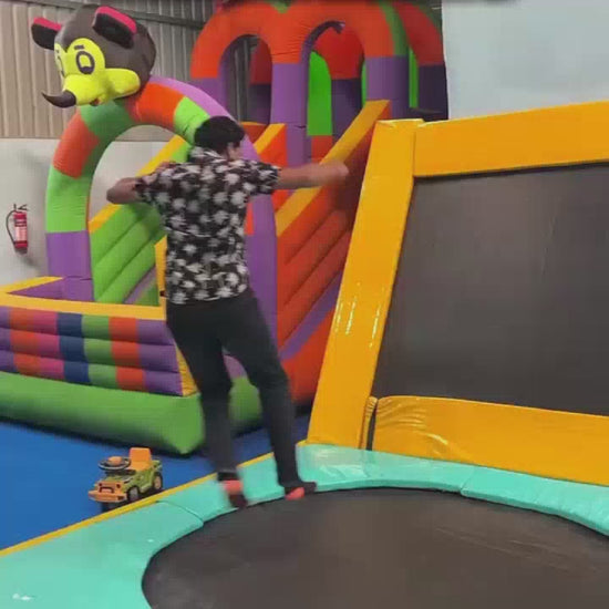 A group of people of various ages enjoys a trampoline park with colorful bouncy structures, foam pits, and inflatable balls. The atmosphere is lively and energetic as individuals jump, slide, and play.