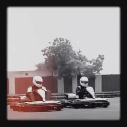 Go-karting enthusiasts of all ages race on a 650-meter track engineered for real racing. The atmosphere is thrilling, with karts speeding around the track, surrounded by tire barriers and floodlights for nighttime racing. The equipment includes sleek go-karts and helmets, ensuring a safe and exciting experience.