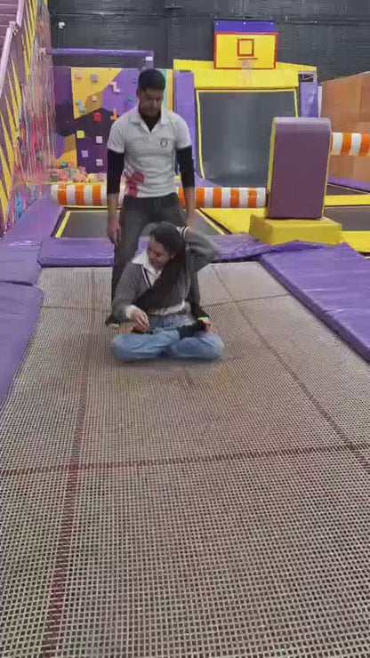 Adults being bounced on a trampoline at an indoor trampoline park, enjoying high-energy jumping fun and active entertainment.
