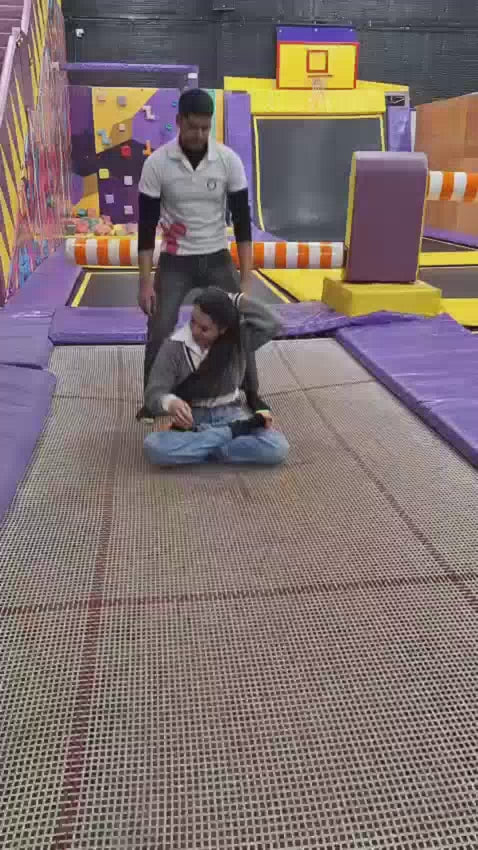 Adults being bounced on a trampoline at an indoor trampoline park, enjoying high-energy jumping fun and active entertainment.