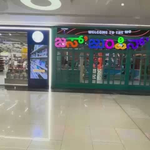 A vibrant indoor play area, "Just Jumpin'," offers a fun-filled experience for young children. The space features a ball pit, slides, trampolines, and a climbing wall, creating a lively and energetic atmosphere. Children of various ages are seen actively engaged in play, enjoying the colorful and safe environment.