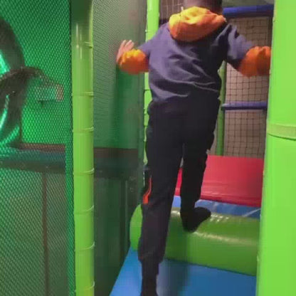 A young boy enjoys a vibrant indoor playground with colorful slides, ball pits, and climbing structures. He navigates obstacles, plays in a ball pit, and slides down, showcasing a lively and fun atmosphere for children.
