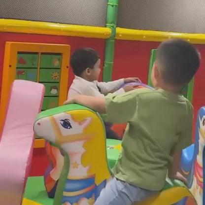 Young children enjoy a vibrant indoor play area with colorful ball pits, slides, and bouncy trampolines. The atmosphere is lively and playful as kids climb, slide, and interact with the various attractions. A young boy is seen enjoying a juice box and fries at a table.