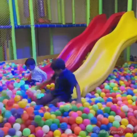 Children aged 13 and under enjoy a vibrant indoor play area filled with slides, ball pits, climbing walls, and trampolines. The atmosphere is energetic and fun, with kids actively playing and laughing. This gadget-free zone offers a variety of attractions designed for active engagement and entertainment.