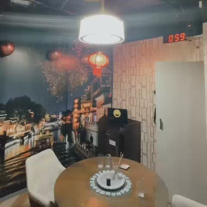 A group of young adults are engaged in an escape room challenge, navigating a room decorated with Chinese lanterns and a cityscape mural. They interact with various puzzles, including a roulette-style game and a locked briefcase, under the pressure of a ticking clock. The atmosphere is one of focused excitement and teamwork as they race against time to solve the mysteries.