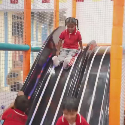 Children and adults enjoy a vibrant indoor play area with slides, ball pits, and arcade games like bowling and claw machines. The atmosphere is lively and fun, with bright colors and engaging attractions for various age groups.