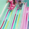 A woman and a young boy enjoy a colorful indoor playground, sliding down a vibrant slide and engaging in various play activities like building blocks, playing doctor, and digging in a sandpit. The atmosphere is cheerful and playful, with bright decorations and interactive stations designed for young children.