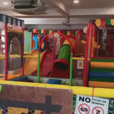 A vibrant indoor playground with colorful slides, tunnels, and swings offers a fun-filled environment for young children. The soft, padded flooring and safety nets ensure a secure play area, while cartoon characters adorn the walls, creating a cheerful and engaging atmosphere.
