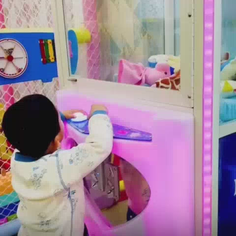 Children of various ages enjoy a vibrant indoor playground filled with colorful slides, ball pits, and punching bags. The atmosphere is lively and playful, with kids actively engaged in sliding, climbing, and interacting with the attractions. The soft, padded environment suggests a safe and fun space for young children to play.