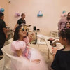A vibrant birthday party unfolds with children and adults enjoying various attractions like trampolines and ball pits. The atmosphere is festive, with colorful decorations and a sense of excitement. The venue appears to be an indoor entertainment center, designed for fun and celebration.