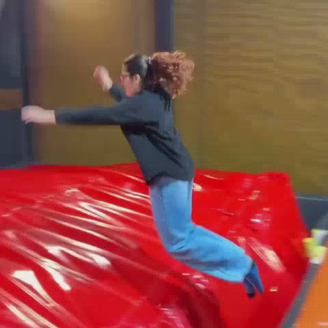 A group of young adults enjoys a vibrant arcade, engaging in activities like rock climbing, bowling, and various video games. The atmosphere is energetic and fun, with colorful lights and exciting attractions like racing simulators and claw machines.