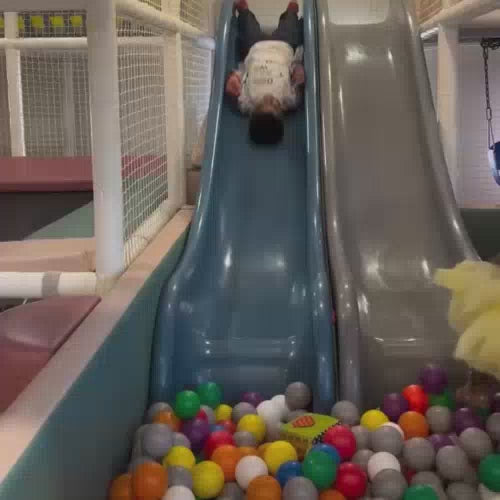 Children of various ages enjoy a vibrant indoor play area filled with slides, ball pits, and ride-on toys. The atmosphere is lively and playful, with kids actively engaging in different activities. The environment is colorful and safe, designed for fun and exploration.