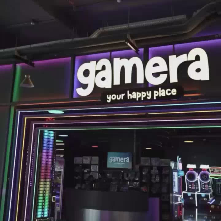 A vibrant arcade filled with neon lights and various games like air hockey, bowling, and racing simulators. People of all ages are enjoying themselves, from young children to adults, creating a lively and fun atmosphere. The space is equipped with modern gaming machines and attractions, offering a complete entertainment experience.