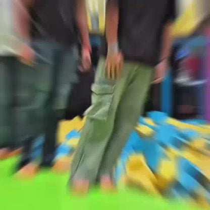 Young adults enjoy a trampoline park with foam pits and inflatable obstacles. The atmosphere is energetic and playful as they jump, tumble, and interact. The bright, colorful equipment creates a fun and engaging environment.