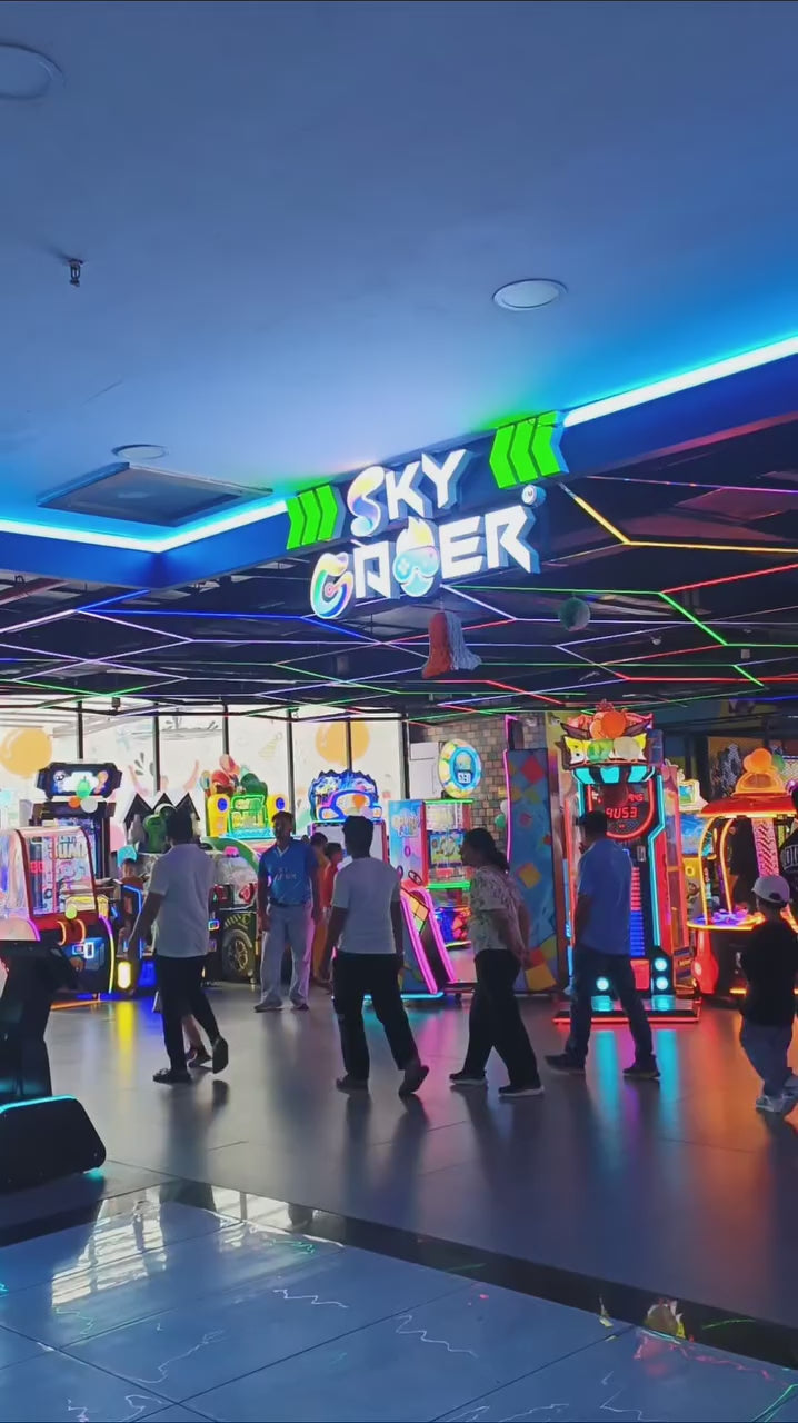 Kids and adults enjoying an indoor gaming zone with arcade machines, racing games and interactive play setups, offering fun and engaging entertainment activities.