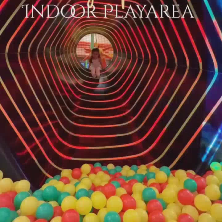 A vibrant indoor play area filled with colorful balls, slides, and climbing structures. Children of various ages enjoy the exciting activities, creating a lively and joyful atmosphere. The play area features a ball pit, a tube slide, and interactive games, offering endless fun for young adventurers.