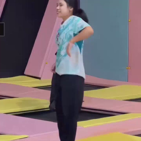 A group of young people enjoys a vibrant indoor adventure park, filled with trampolines, ball pits, slides, and go-karts. They laugh and play, experiencing various attractions like a zip line and a rope bridge. The atmosphere is energetic and fun, with colorful equipment and playful decor.